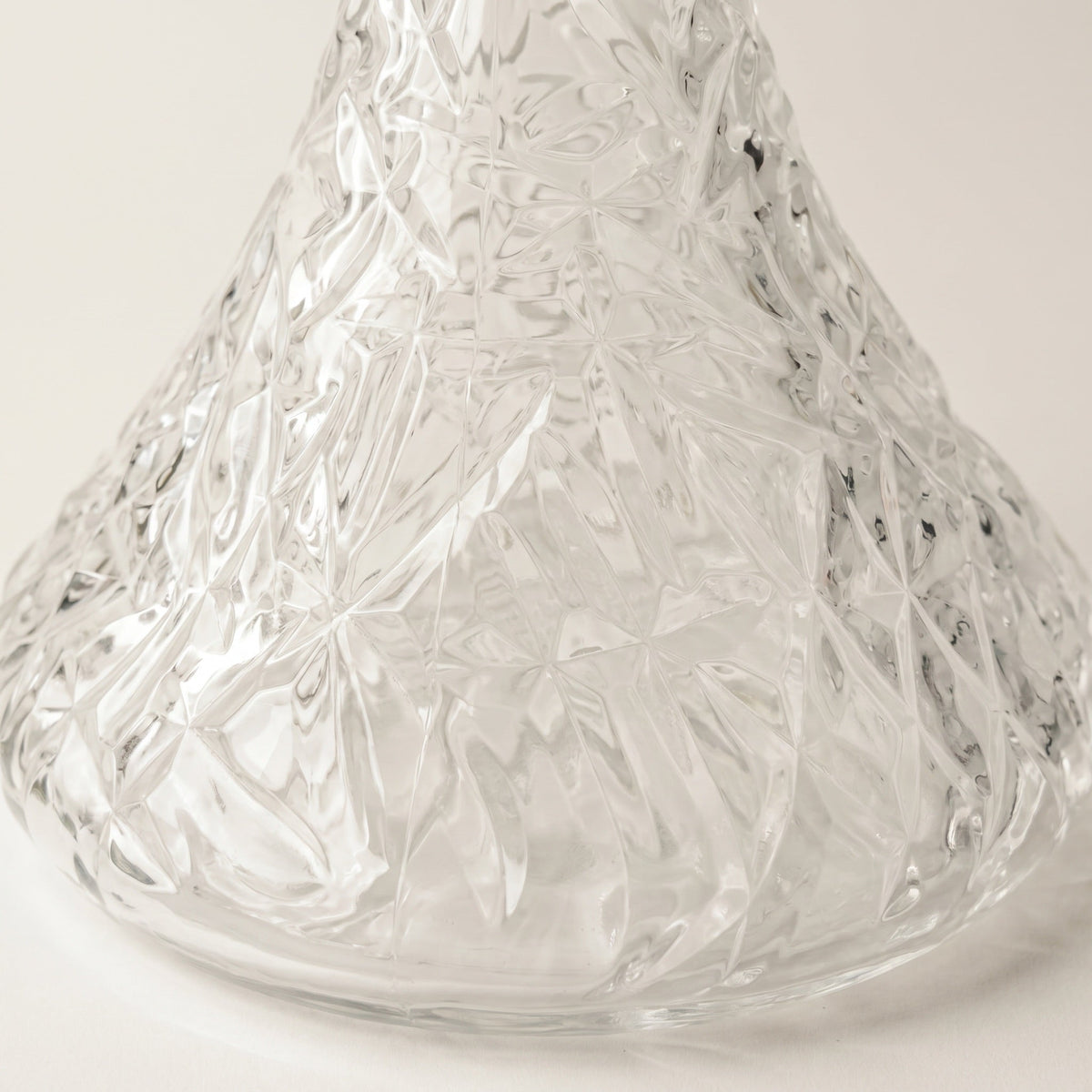Essentials Crystal-Cut Clear Russian shisha vase on travertine plinth, refracted light fanning across the wall behind, image 4 of 4