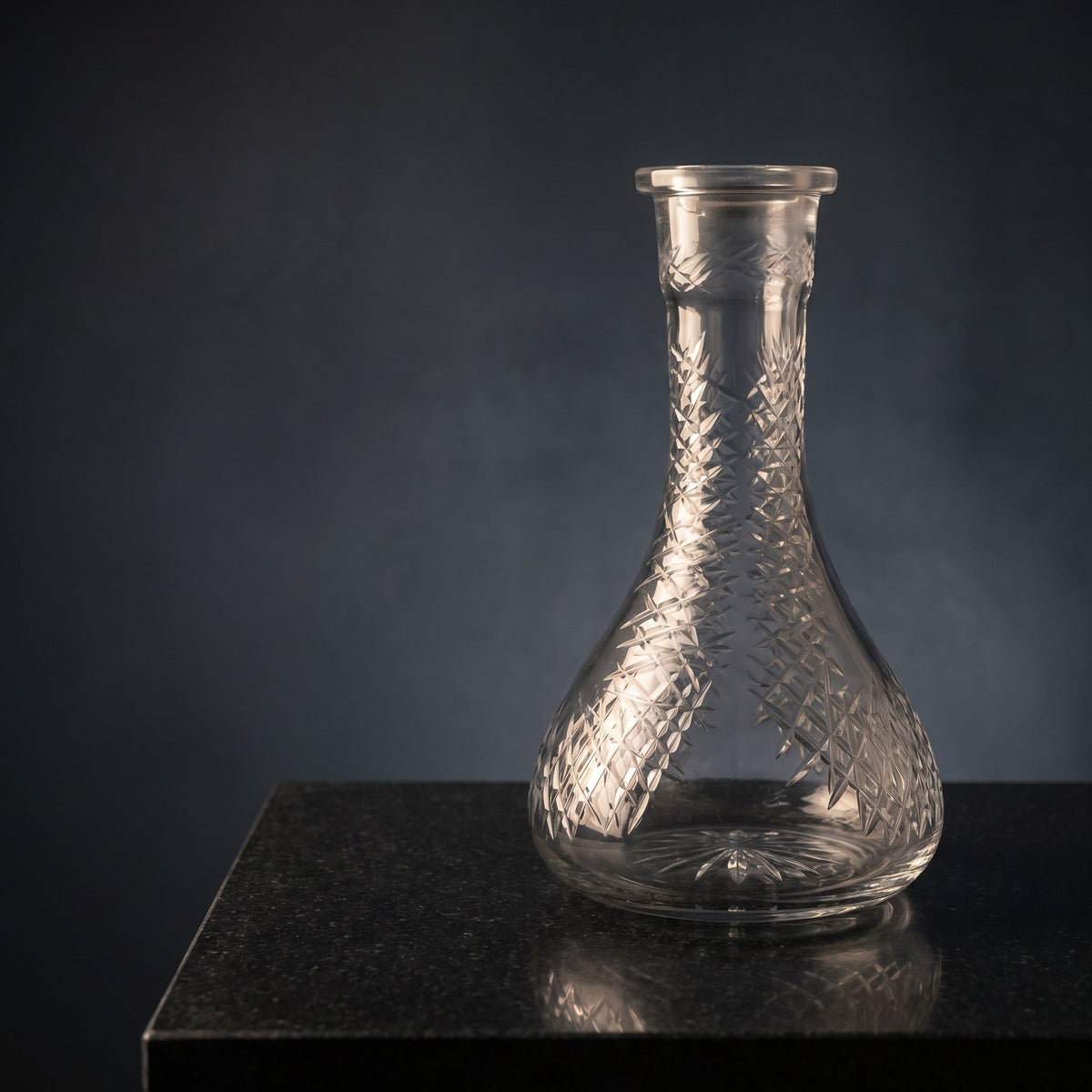 Essentials Etched Diamond Clear shisha vase on polished dark stone, warm key light catching the diamond hatch cuts across the clear glass body, image 2 of 3