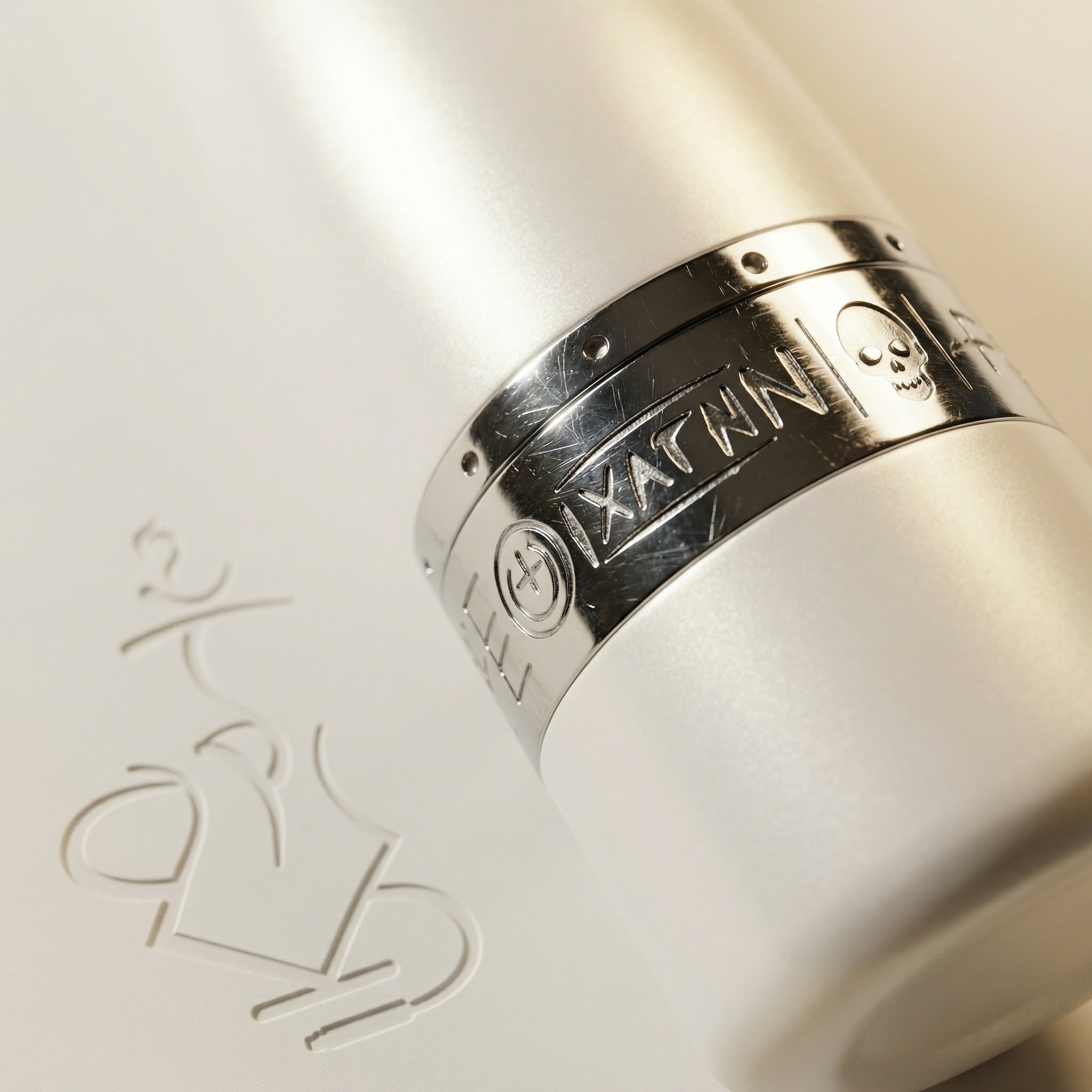 Macro detail of the engraved chrome purge collar on the Hooligan White Baseball Bat Hookah, showing the hand-engraved Hooligan graffiti band where the chrome meets the pearlescent white stem.