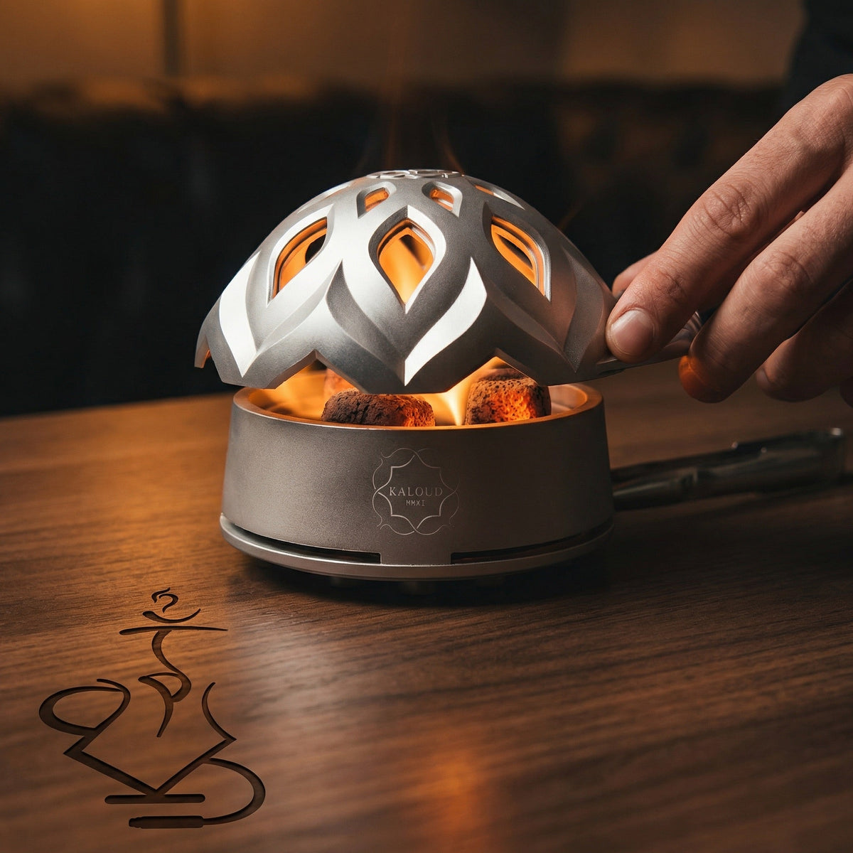 Kaloud Lotus I+3 Argis Silver HMD with glowing coconut coals visible through the lotus lid cutouts, hand lifting the lid during a hookah session on a walnut bar top., image 12 of 19