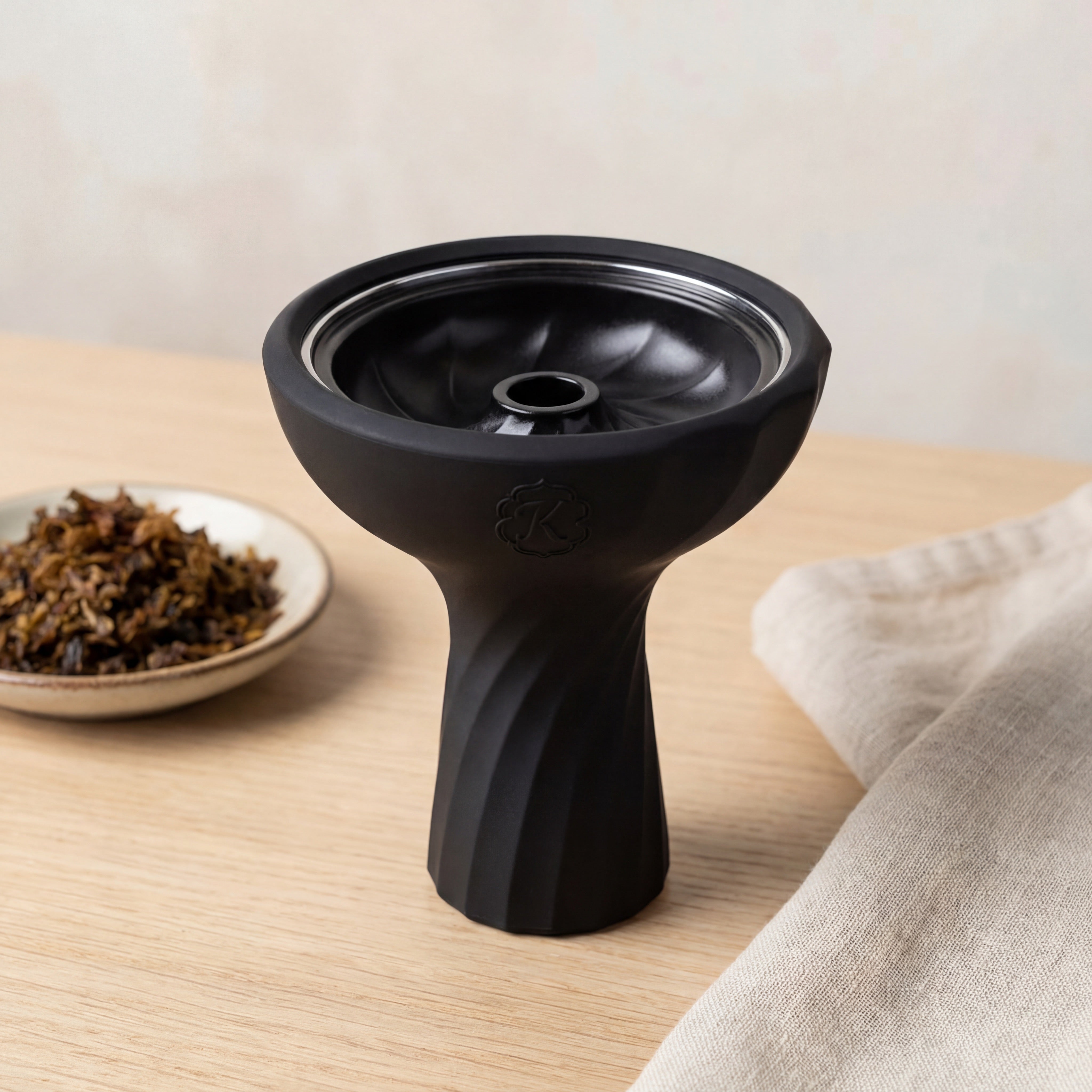 Kaloud Samsaris Lapis II ceramic shisha bowl on pale oak surface with shisha leaf in ceramic dish and linen cloth