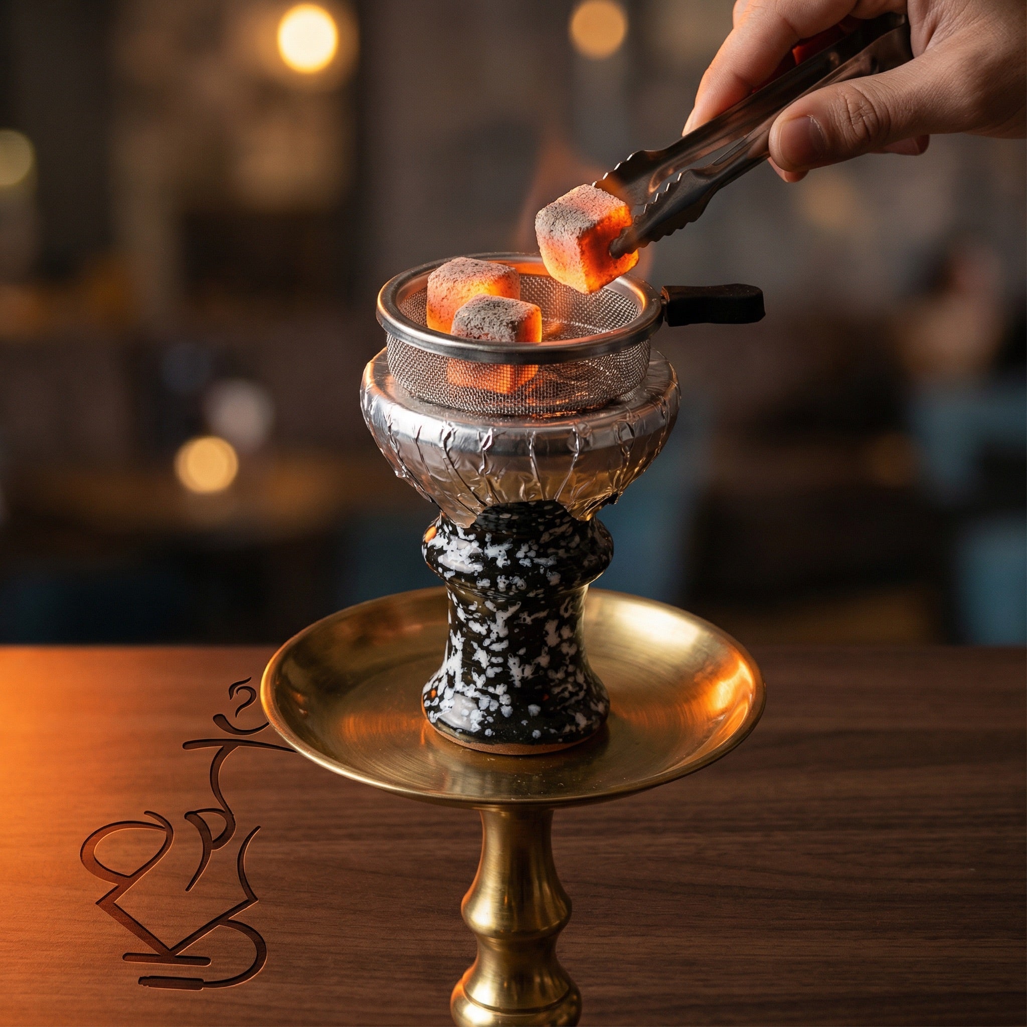 Khalil Mamoon marble ceramic bowl mounted on a hookah with glowing coals and Provost screen, hand placing charcoal with tongs during a session