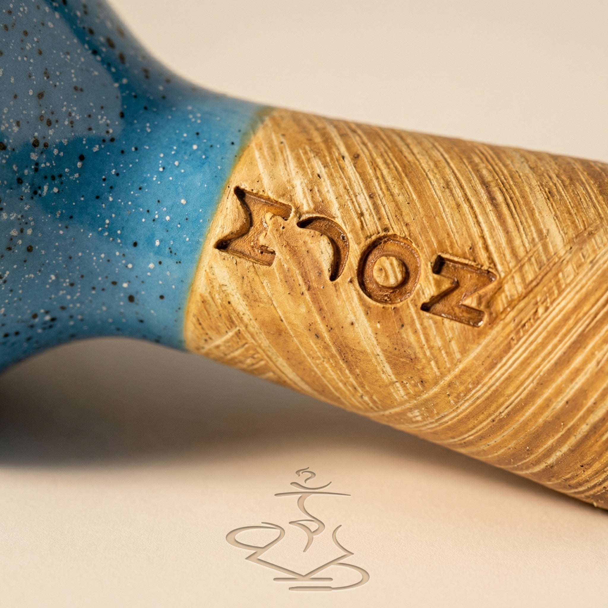 Macro detail of the Moon Phunnel showing the speckled blue glaze meeting raw tan clay and the hand-stamped MOON wordmark pressed into the wheel-thrown surface.