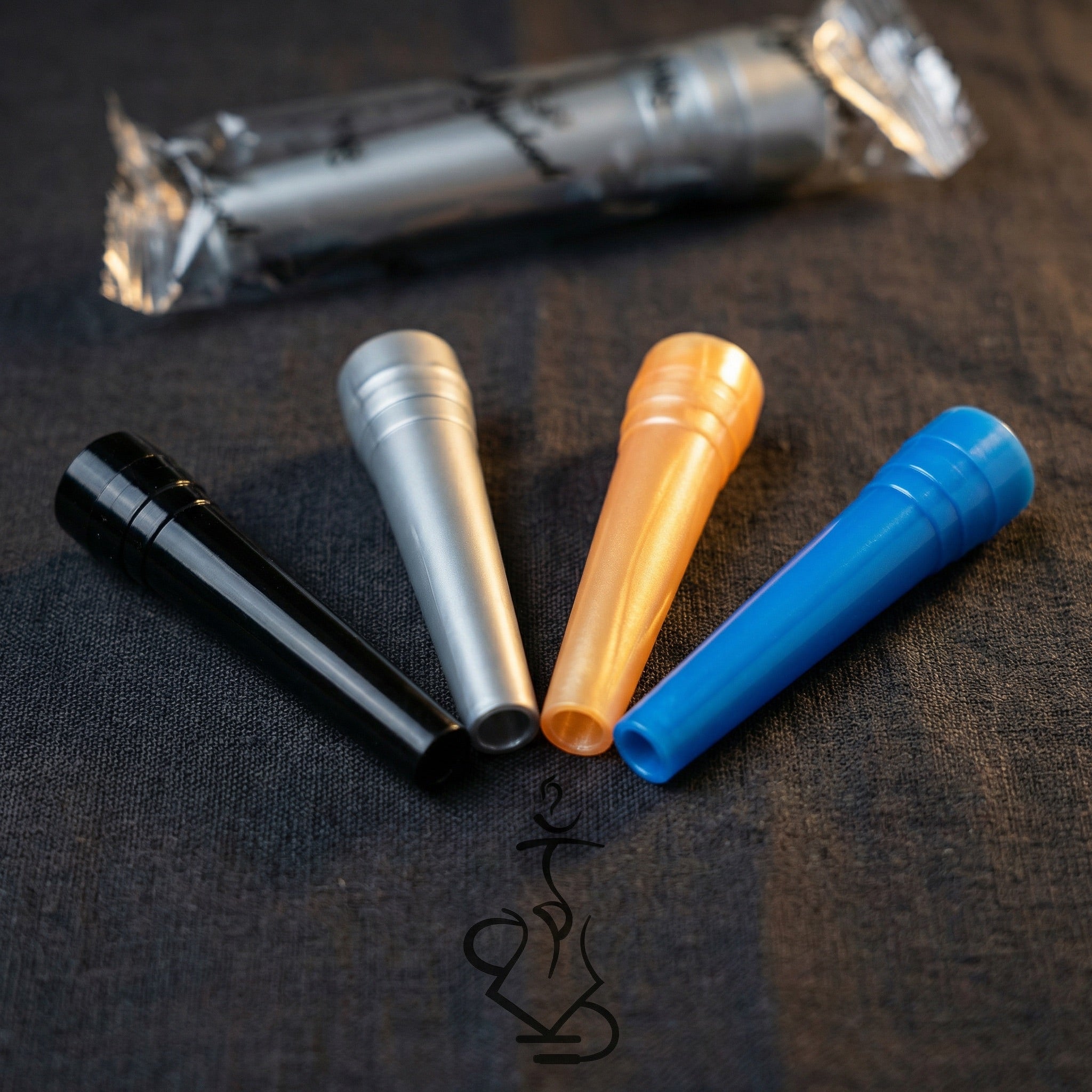 Close-up detail of four ShishaDoc disposable hookah mouth tips in blue, black, silver, and orange arranged in a fan with wrapped tip showing individual packaging