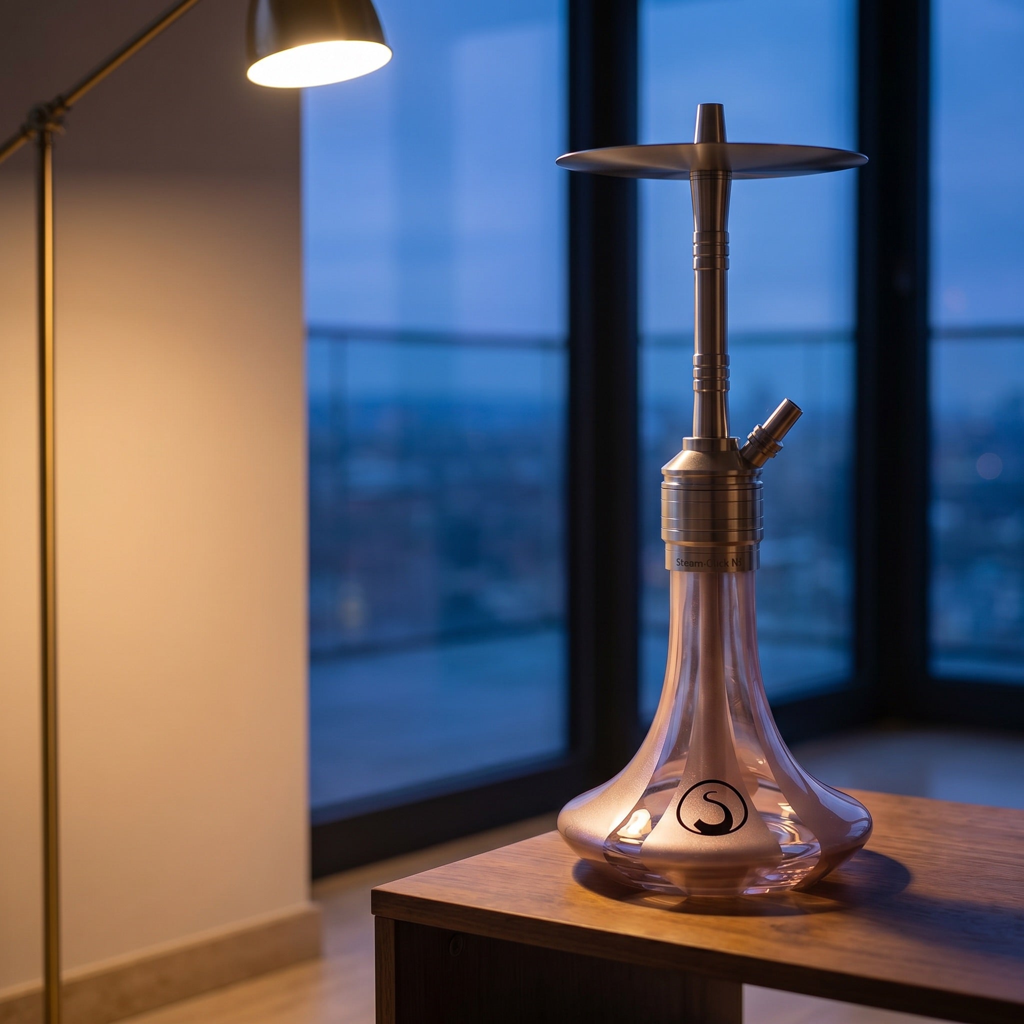 Steamulation Mini Gen II Rose Metallic on walnut table in modern apartment at dusk, brass lamp light, city view